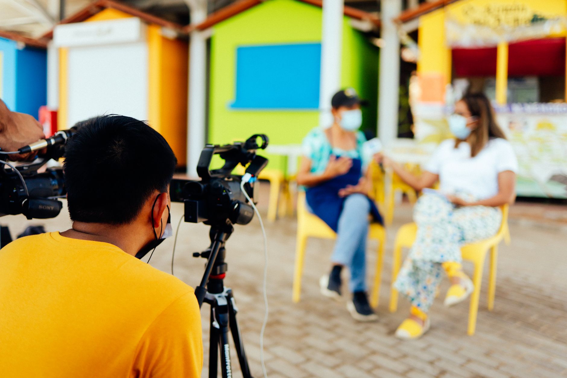 Équipe de tournage filmant une interview en extérieur avec des participants masqués pour un documentaire.